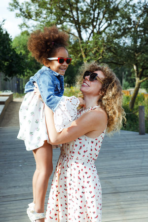 A beautiful young mother plays with her little daughter in a park near the beach. Having fun and feeling happy.の写真素材