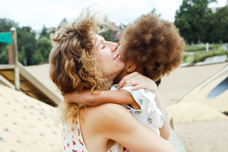 A young mother holds her little daughter in her arms. Relaxation on the beach. Happy childhood.の写真素材