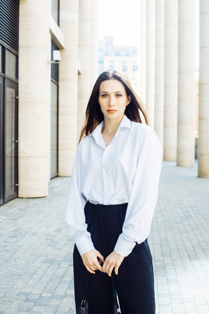 Fashionable woman. Young female model with long hair wears white shirt and black paints. Summer day.の写真素材