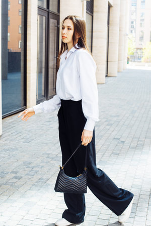 Fashionable woman. Young female model with long hair wears white shirt and black paints. Summer day.の写真素材