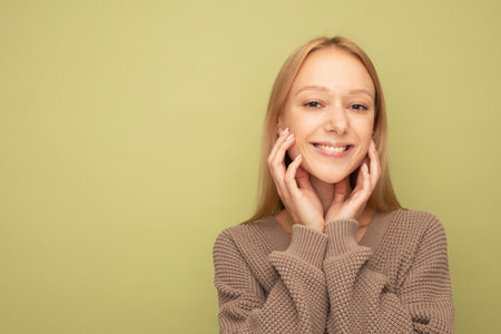 young woman with blond hair smiling isolated over olive color backgroundの写真素材
