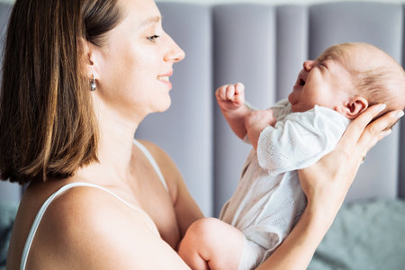 A loving mother hugs her baby. A young mom holds a baby in her arms and kisses him. Motherhood and...