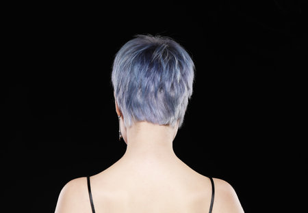 Young woman with stylish short haircut and colored hair dyeing - blue-green hair. Close-up portrait, back view.の写真素材
