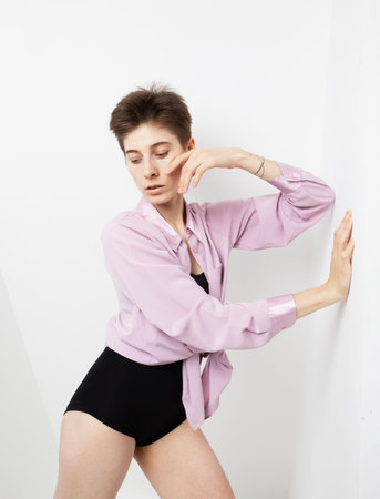 Stylish fashion woman model with short haircut in pink shirt posing on white background.の写真素材