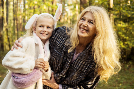 Seven year old girl with her grandmother in an autumn park. Happy time.の写真素材