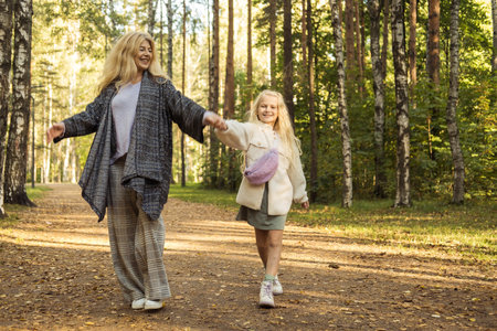 Seven year old girl with her grandmother in an autumn park. Happy time.の写真素材