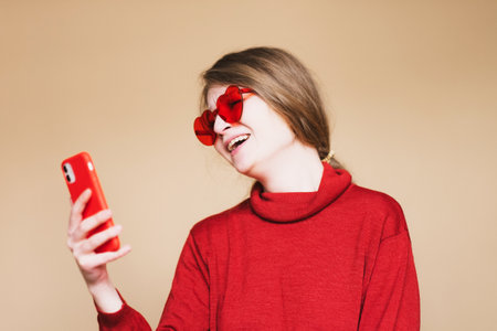 lifestyle, emotional and people concept: beautiful young woman with smart phone take selfie over beige background.の写真素材
