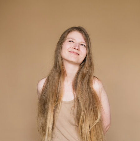 Studio shot of good-looking beautiful woman with long hair isolated against beige background.の写真素材