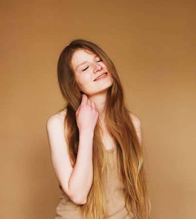 Studio shot of good-looking beautiful woman with long hair isolated against beige background.の写真素材