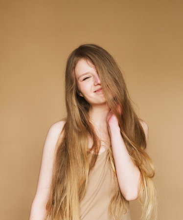 young woman smiling sincerely on beige background.の写真素材