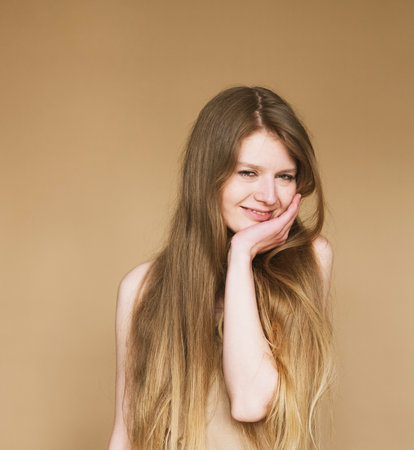 young woman smiling sincerely on beige background.の写真素材