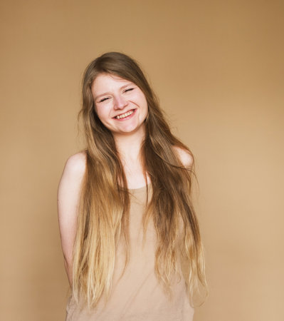 cheerful happy young woman laughing sincerely on beige background.の写真素材