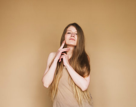 young woman smiling sincerely on beige background.の写真素材