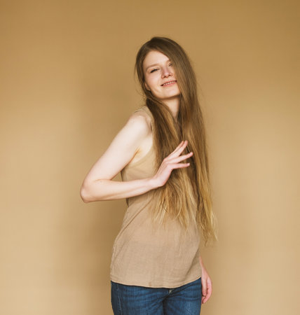 young woman smiling sincerely on beige background.の写真素材