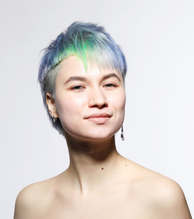 Beautiful young woman with stylish short haircut and colored hair dyeing - blue-green hair. Close-up portrait over light gray background.の写真素材