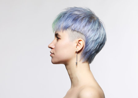 Profile of young woman with stylish short haircut and colored hair dyeing - blue-green hair. Close-up portrait, side view.の写真素材