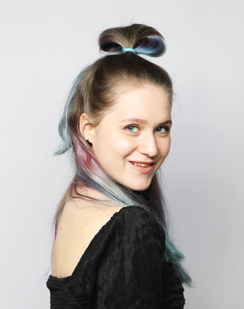 Beautiful young woman with stylish colored hair dyeing - blue-pink hair. Close-up portrait over light gray background.の写真素材