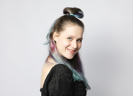 Beautiful young woman with stylish colored hair dyeing - blue-pink hair. Close-up portrait over light gray background.の写真素材