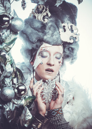 Beautiful young woman with bright creative make-up in New Years costume posing with her eyes closedの写真素材
