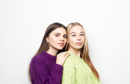 Two young cheerful girlfriends laughing and hugging on a white background.の写真素材