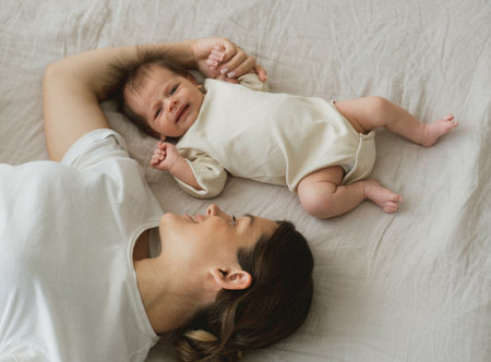 Portrait of a newborn baby with young mother on the bed.の写真素材