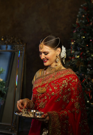 Charming young women holds jewelry on a saucer. Traditional Indian wedding sari and jewelry.の写真素材