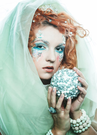 Beautiful redhead woman in christmas party costume holding christmas ball.の写真素材