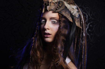 Close up portrait of young woman with bright makeup, braids and a skull on her headの写真素材