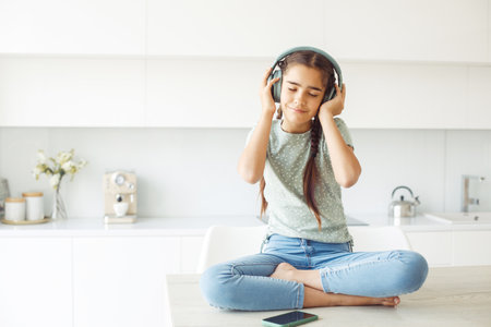 Cute girl with pigtails with headphones listening to music at homeの写真素材