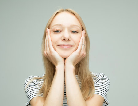 Attractive woman with blond hair smiling isolated over light grey color background.の写真素材