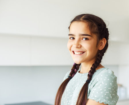 Charming smiling ten-year-old girl with pigtails, close-up portrait at home.の写真素材
