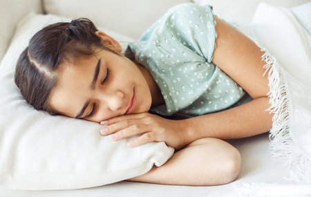 Ten year old girl with pigtails sleeping on the sofa at home.の写真素材