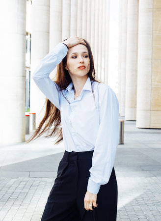 Fashionable brunette woman in the city. Young female model with long hair wears white shirt.の写真素材
