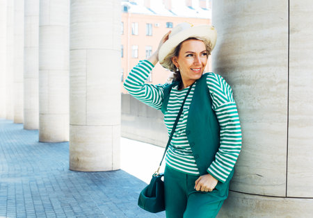 Blond Woman Outdoor Portrait. Green outfit with hat. Fashion trend of summer or spring.の写真素材