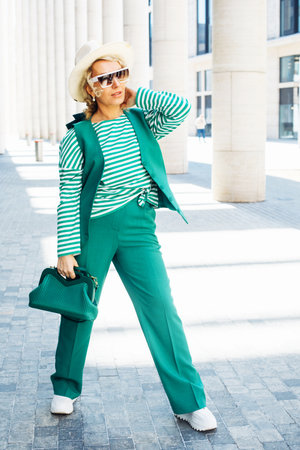 Blond Woman Outdoor Portrait. Green outfit with hat. Fashion trend of summer or spring.の写真素材