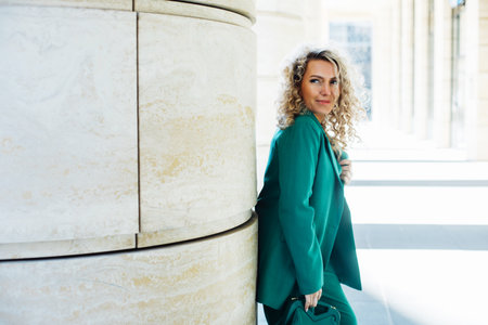 Fashionable woman. Young female model with blond curly hair wears green clothes.の写真素材