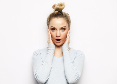surprised young woman over white studio backgroundの写真素材