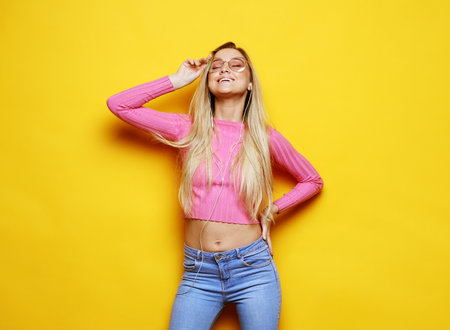 Young cute smiling blond girl over yellow backgroundの写真素材