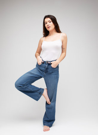 fashion model with long dark curly hair posing in studio over gray backgroundの写真素材