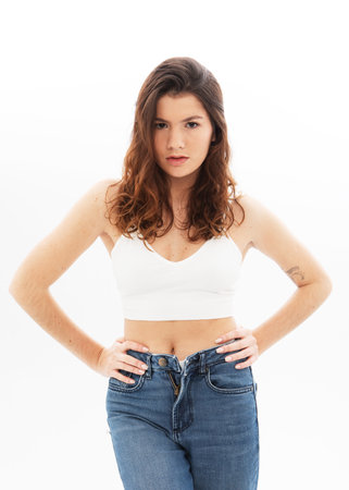 fashion model with long dark curly hair posing in studio over white backgroundの写真素材
