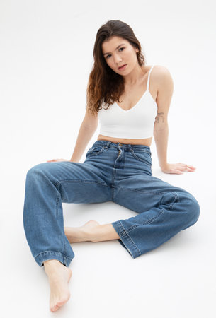fashion model with long dark curly hair posing in studio over white backgroundの写真素材