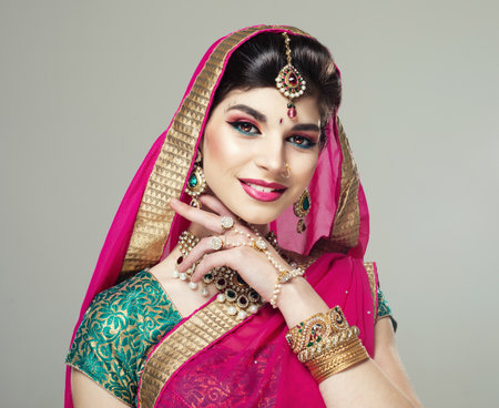 Indian beauty. Gorgeous model wearing in traditional Indian jewelry, with the head covered by veil with gilded edge. Close up.の写真素材