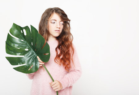 Beauty and fashion concept: Little girl child holding a monstera leaf.の写真素材