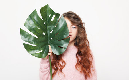 Beauty and fashion concept: Little girl child holding a monstera leaf.の写真素材