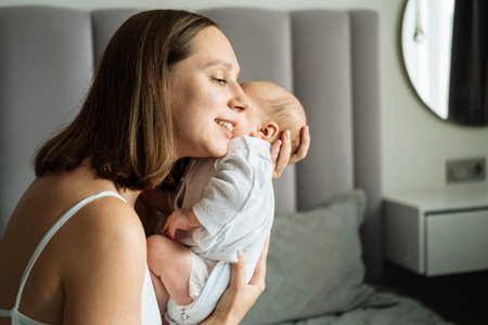 A loving mother hugs her baby. A young happy mother holds a baby in her arms. Motherhood and family concept.の写真素材