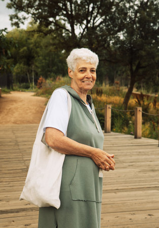 An elderly woman with curly hair walks in a summer park. Lifestyle and people concept.の写真素材