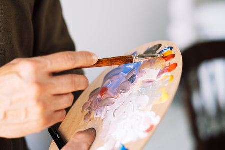 Close-up of male hands holding brushes and palette. Artist ready to create. Art and people concept.の写真素材