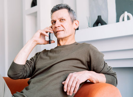 senior man talking on the phone at homeの写真素材