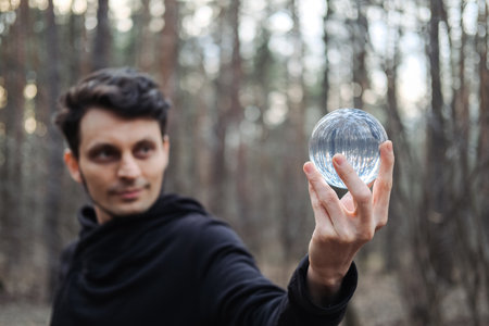 A young man juggles a transparent ball in a forest.の写真素材