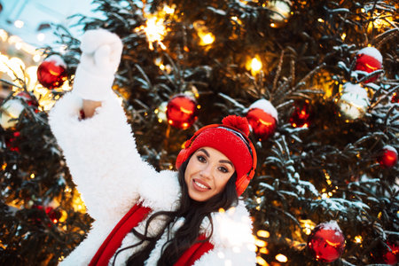 Lovely young brunette woman at the Christmas market next to the New Year tree.の写真素材